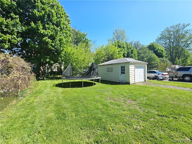 view of yard featuring an outdoor structure, a trampoline, and a garage