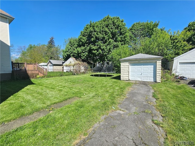 view of yard featuring an outdoor structure, a garage, and a trampoline