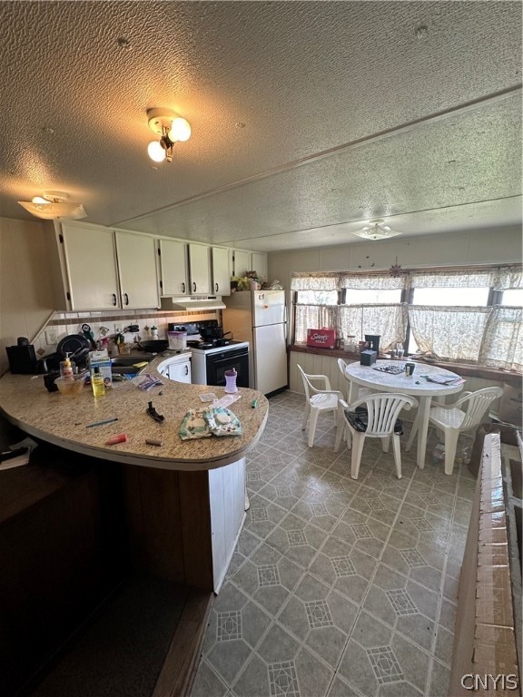 kitchen featuring white appliances, white cabinetry, tile floors, and a textured ceiling