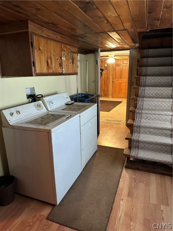 laundry room featuring washer and dryer, cabinets, wooden ceiling, and light wood-type flooring