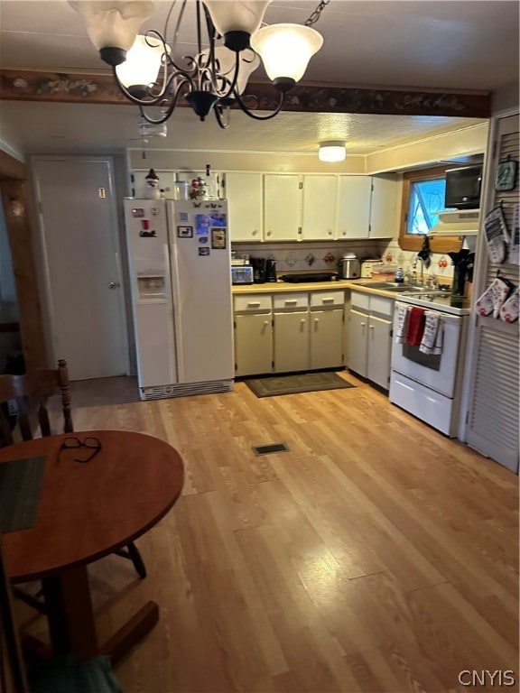 kitchen featuring hanging light fixtures, white appliances, light hardwood / wood-style floors, and an inviting chandelier