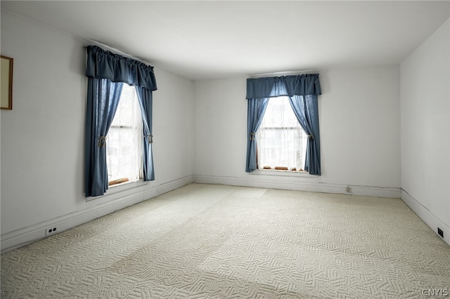 spare room featuring a wealth of natural light and light colored carpet