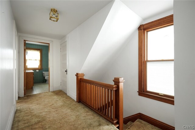 hallway featuring lofted ceiling and light carpet