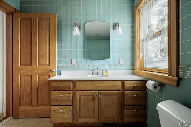 bathroom with toilet, decorative backsplash, vanity, and tile patterned flooring