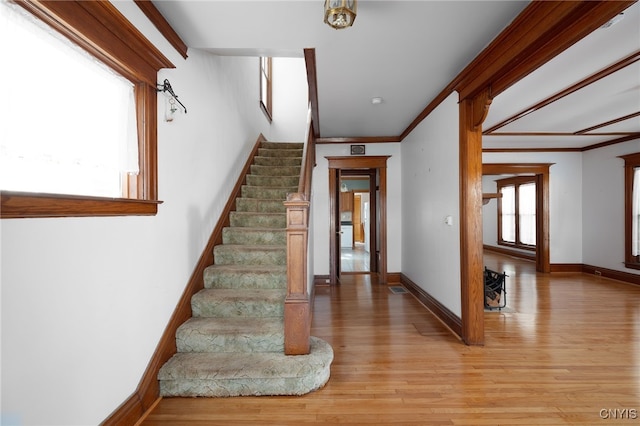 stairs featuring crown molding, hardwood / wood-style floors, and a healthy amount of sunlight