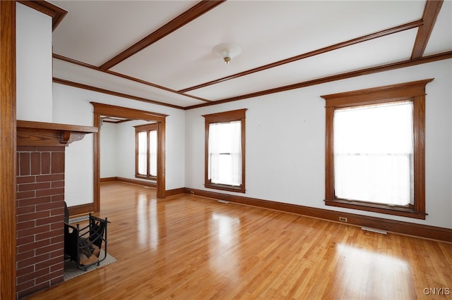 unfurnished living room with crown molding, light hardwood / wood-style floors, a fireplace, and a healthy amount of sunlight