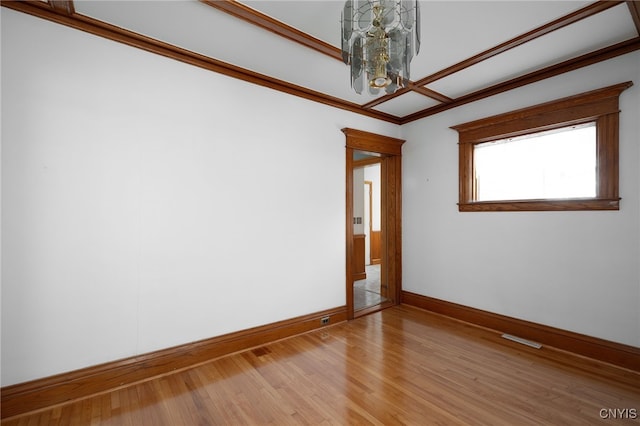 spare room featuring wood-type flooring, ornamental molding, and a chandelier