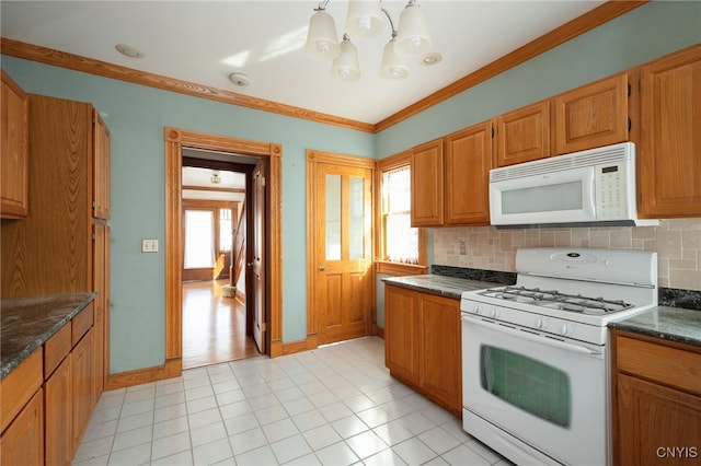 kitchen with crown molding, decorative backsplash, white appliances, and dark stone countertops