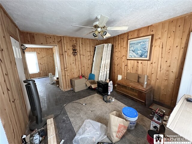 interior space featuring wooden walls, ceiling fan, and a textured ceiling