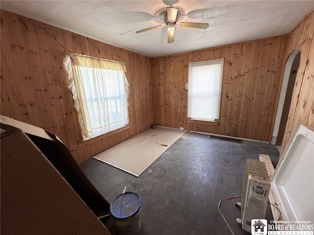 spare room with ceiling fan and wooden walls