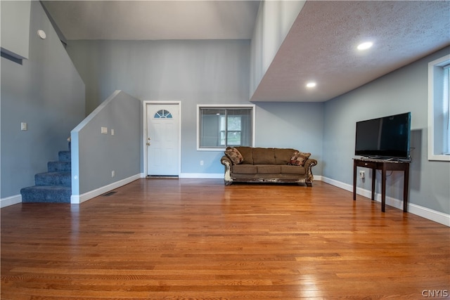 living room featuring a high ceiling, a textured ceiling, and hardwood / wood-style flooring