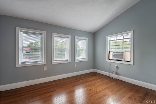 spare room with a wealth of natural light, lofted ceiling, and hardwood / wood-style floors