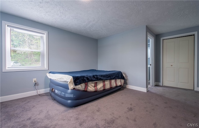 carpeted bedroom featuring a textured ceiling and a closet