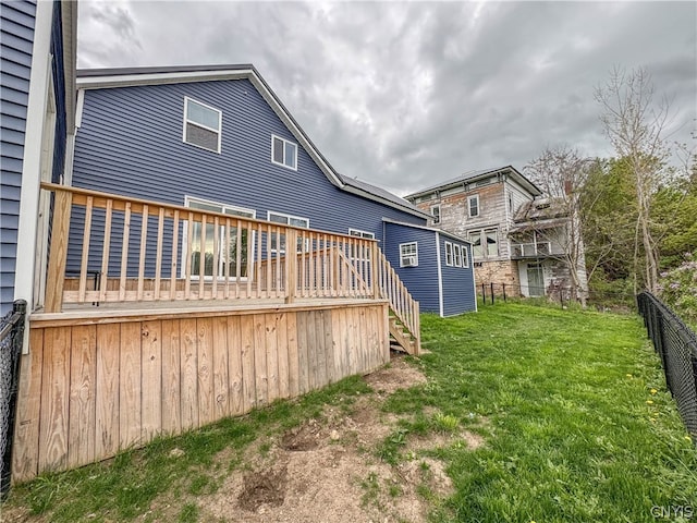 rear view of house featuring a wooden deck and a yard