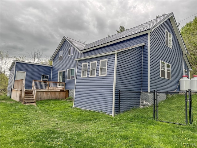 rear view of property with a wooden deck and a lawn