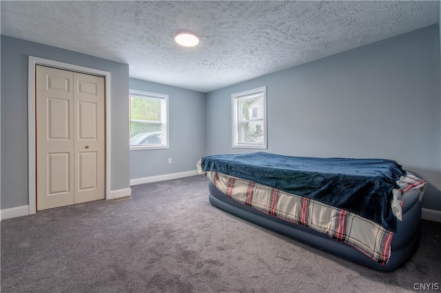 bedroom with a textured ceiling, a closet, and carpet