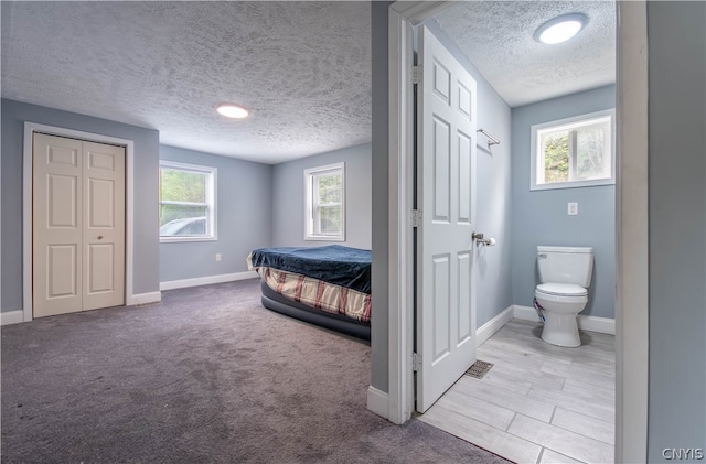 carpeted bedroom featuring multiple windows, a closet, and a textured ceiling