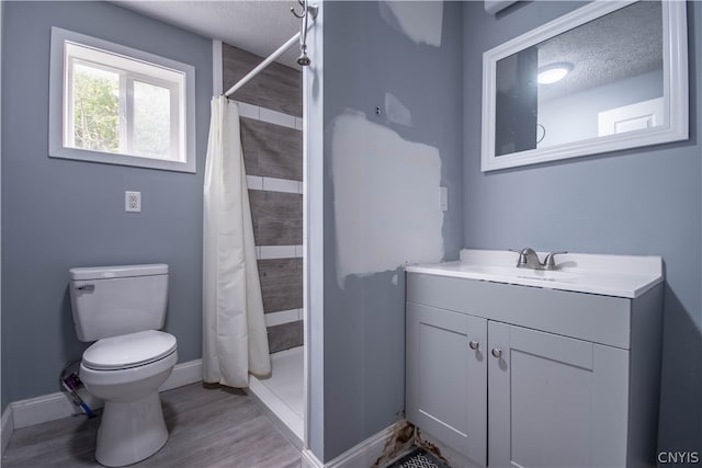 bathroom with wood-type flooring, walk in shower, a textured ceiling, toilet, and vanity