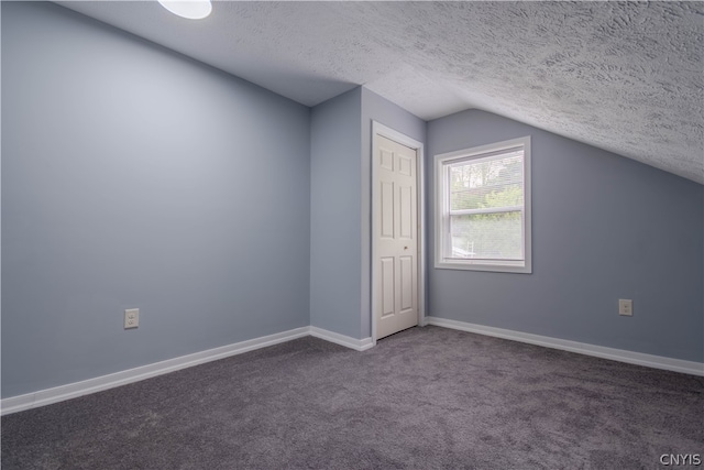 bonus room featuring a textured ceiling, lofted ceiling, and dark colored carpet