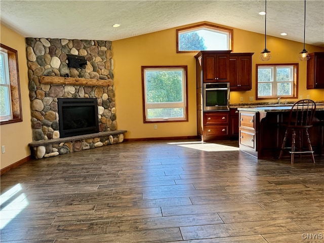 kitchen with hanging light fixtures, a breakfast bar area, a textured ceiling, oven, and lofted ceiling