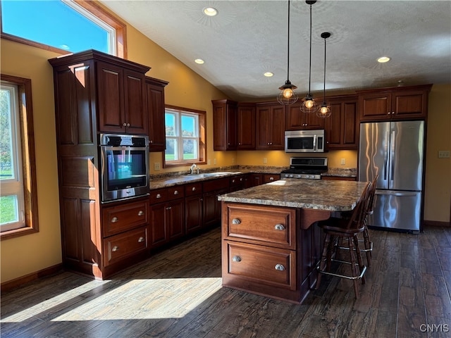 kitchen with stainless steel appliances, dark hardwood / wood-style flooring, lofted ceiling, and a kitchen island