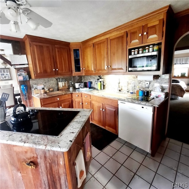 kitchen featuring dishwasher, black electric cooktop, sink, light tile patterned floors, and ceiling fan