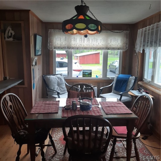 dining area with hardwood / wood-style floors, wooden walls, and a wealth of natural light