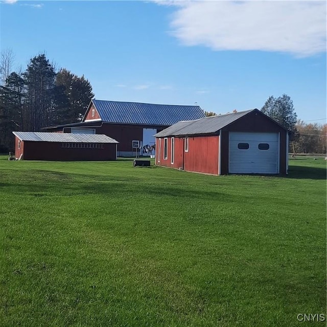 view of yard with a detached garage, an outbuilding, a pole building, and driveway