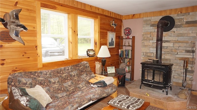 living room with hardwood / wood-style floors, wooden walls, and a wood stove