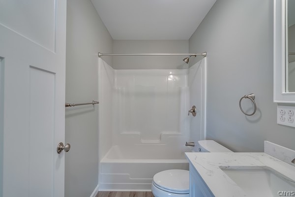 full bathroom featuring hardwood / wood-style flooring, shower / washtub combination, toilet, and vanity with extensive cabinet space