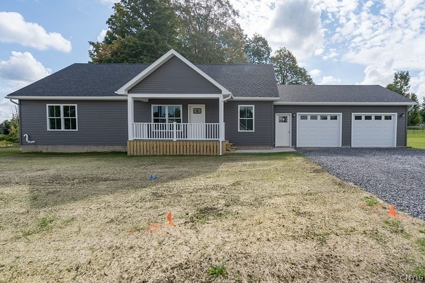 ranch-style home featuring a garage, a front yard, and covered porch