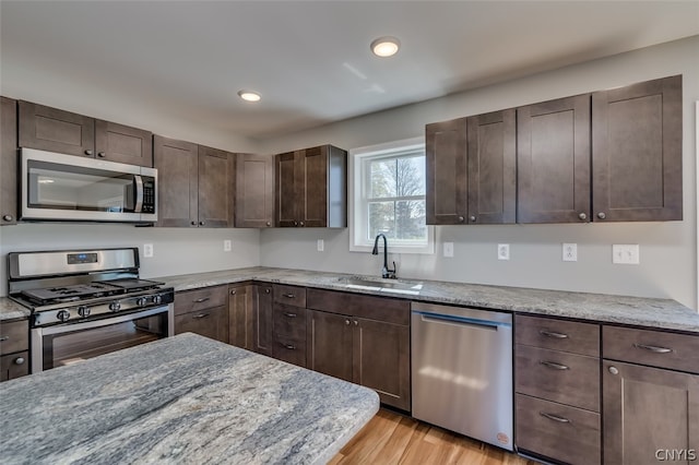22217 Freedom Dr, Champion, NY 13619 - kitchen with light hardwood / wood-style floors, appliances with stainless steel finishes, dark brown cabinets, light stone counters, and sink