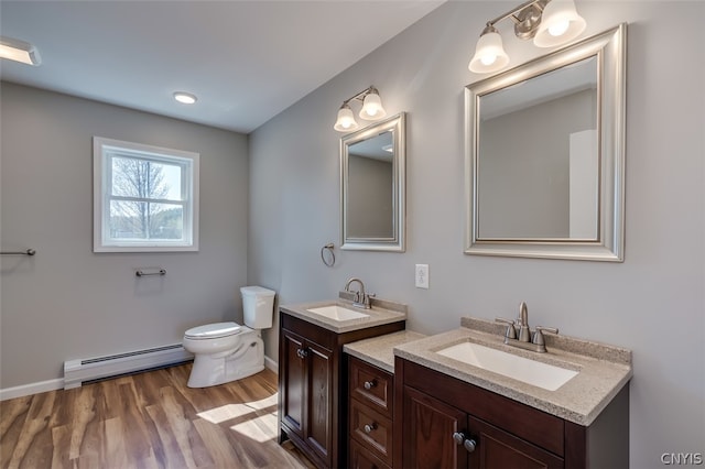 bathroom featuring hardwood / wood-style floors, double sink vanity, toilet, and a baseboard heating unit