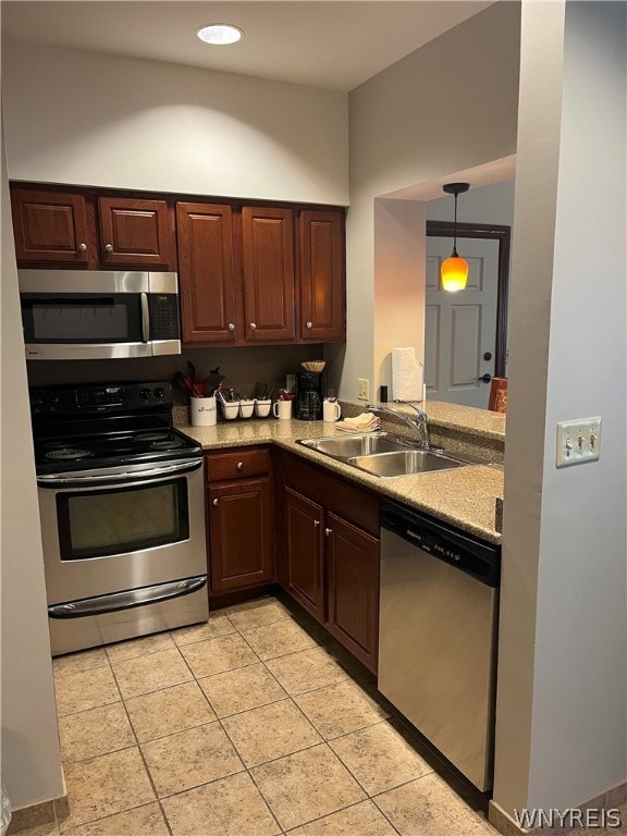 kitchen featuring dark brown cabinetry, stainless steel appliances, sink, light tile floors, and pendant lighting