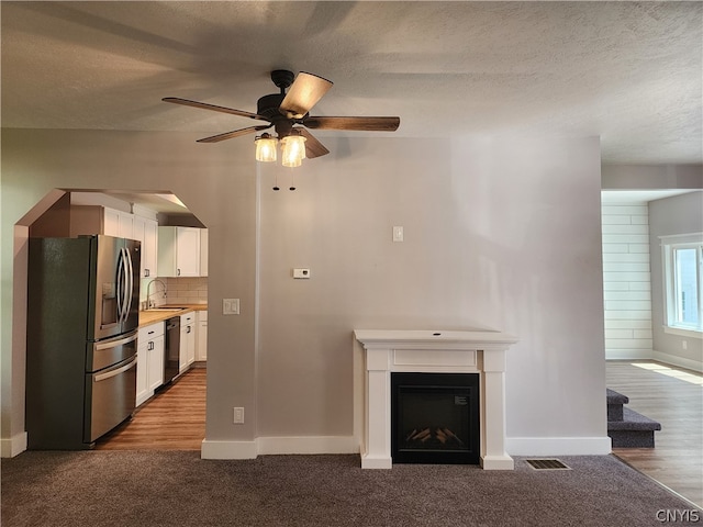 kitchen with ceiling fan, white cabinetry, stainless steel fridge with ice dispenser, and carpet floors