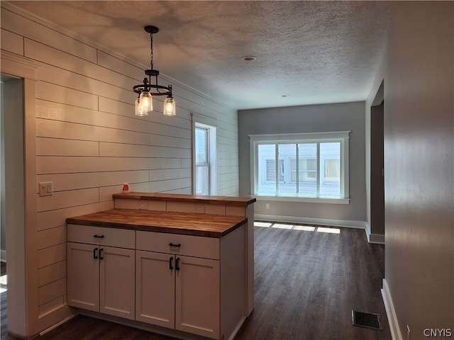 kitchen featuring decorative light fixtures, dark hardwood / wood-style flooring, wood counters, and a textured ceiling