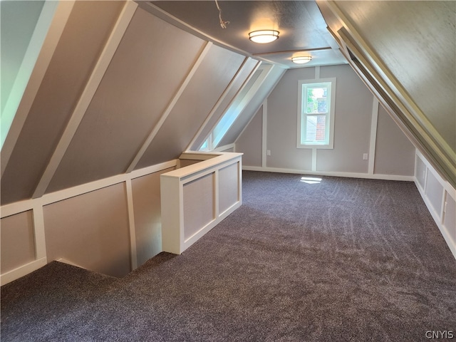 bonus room with dark colored carpet and lofted ceiling