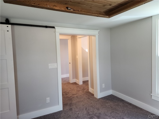 carpeted spare room with a barn door and wooden ceiling