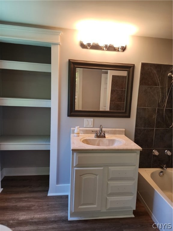 bathroom featuring wood-type flooring, tiled shower / bath, and vanity