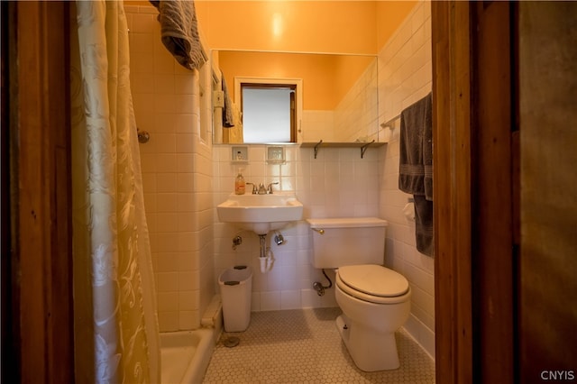 bathroom featuring toilet, tile patterned flooring, sink, curtained shower, and tile walls