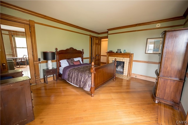 bedroom with crown molding, a fireplace, and light hardwood / wood-style floors