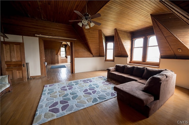 living room with light wood-type flooring, ceiling fan, wooden ceiling, vaulted ceiling, and wooden walls