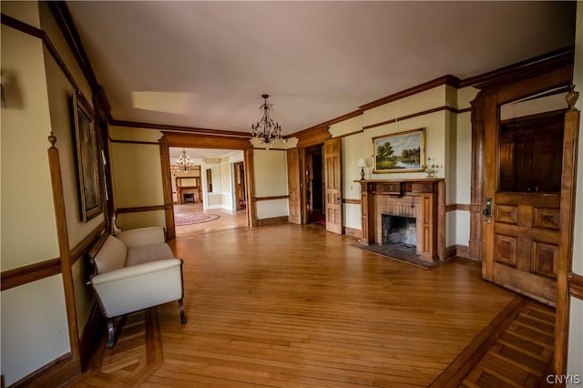 living room featuring light hardwood / wood-style floors, ornamental molding, a chandelier, and a fireplace