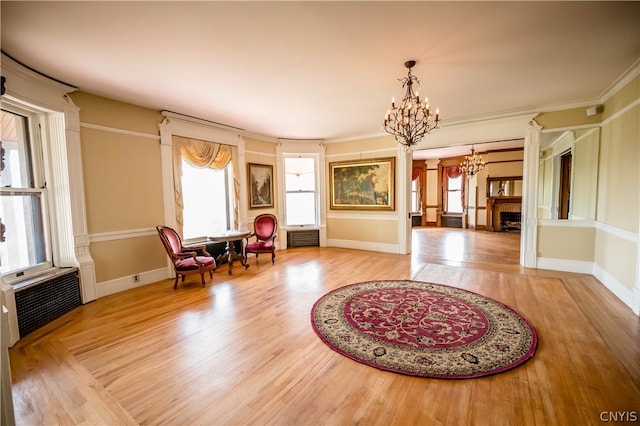 living area featuring crown molding, a notable chandelier, and light wood-type flooring