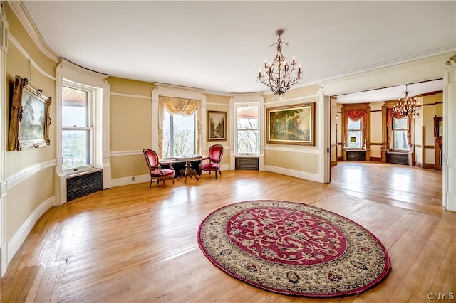 sitting room featuring light hardwood / wood-style flooring, ornamental molding, a healthy amount of sunlight, and a chandelier