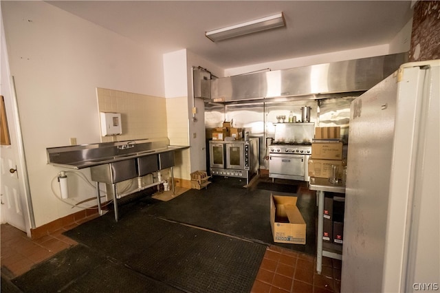 kitchen featuring dark tile patterned floors, stainless steel counters, high end stainless steel range oven, and white refrigerator