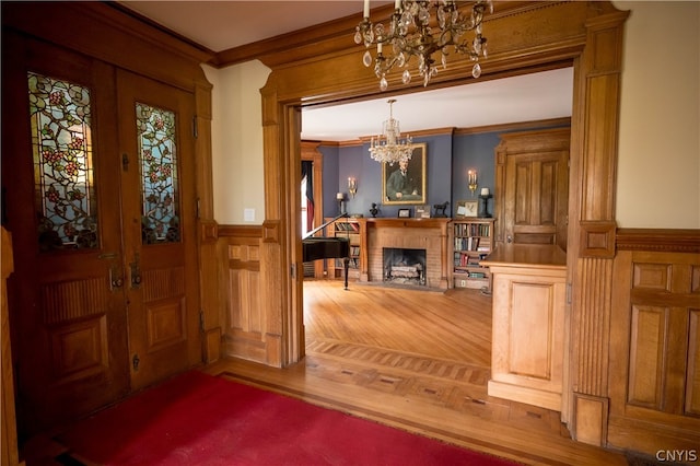 entrance foyer with a notable chandelier, crown molding, and a brick fireplace