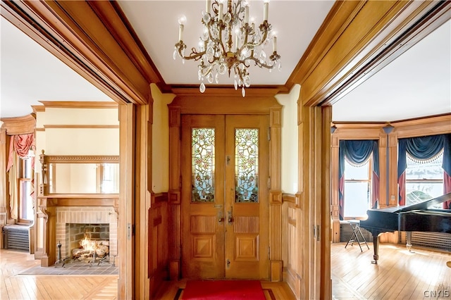 entrance foyer featuring crown molding, light parquet flooring, a chandelier, and a fireplace