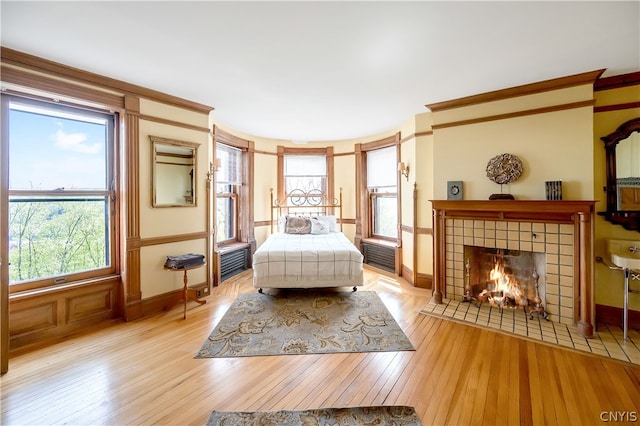 bedroom featuring light hardwood / wood-style flooring and a tiled fireplace