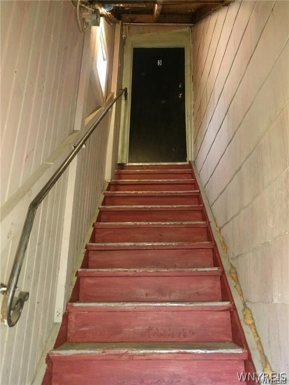 stairway featuring wood walls